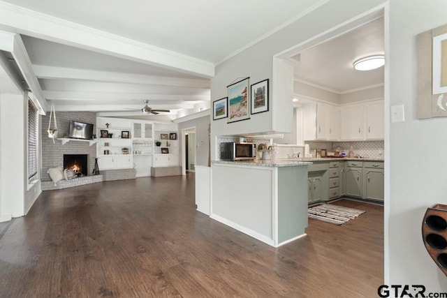 kitchen with stainless steel microwave, a brick fireplace, open floor plan, white cabinetry, and a peninsula