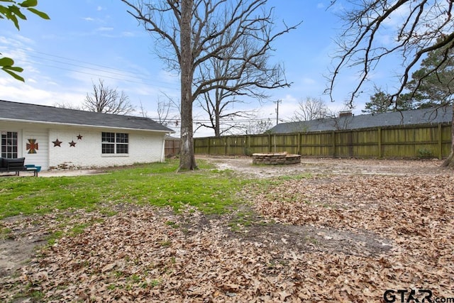 view of yard featuring a fenced backyard and a fire pit