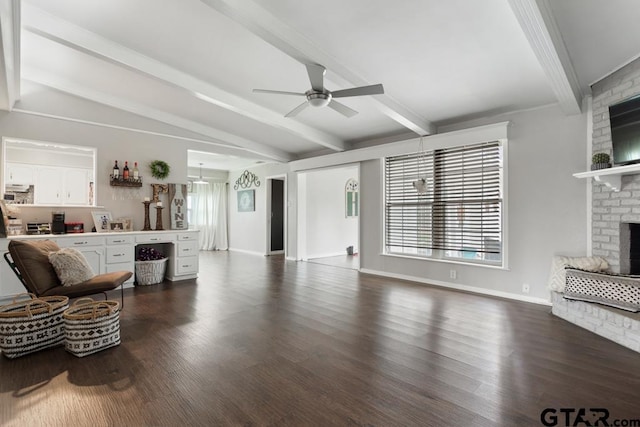 living area featuring dark wood-style flooring, lofted ceiling with beams, a ceiling fan, a brick fireplace, and baseboards