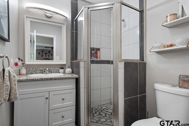 bathroom featuring a stall shower, vanity, and toilet