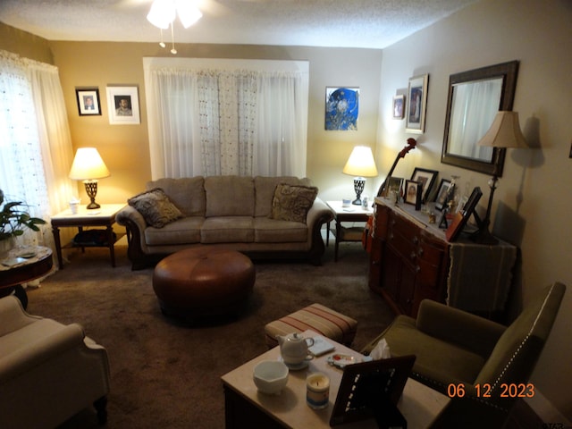 living room featuring a textured ceiling, dark carpet, and ceiling fan