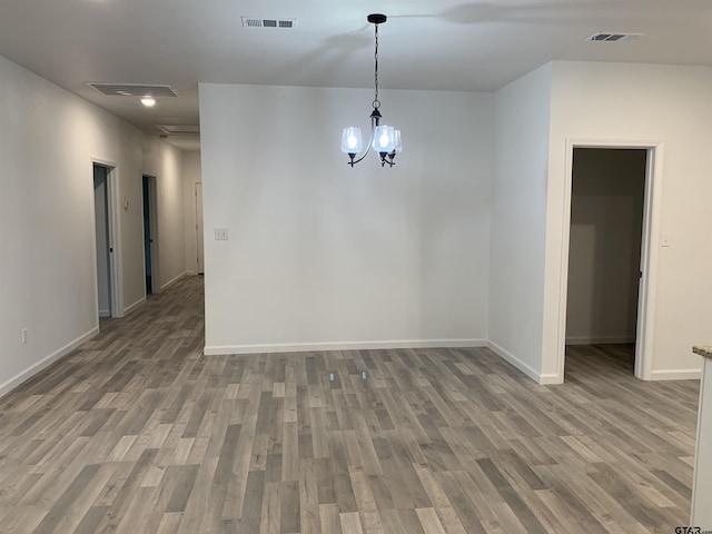 spare room featuring wood-type flooring and a chandelier