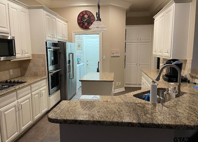 kitchen with decorative backsplash, white cabinetry, a kitchen island, and washing machine and dryer