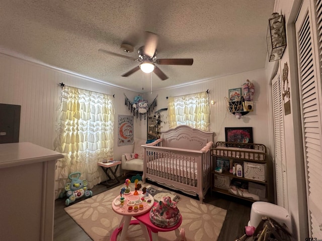 bedroom with hardwood / wood-style floors, a crib, and a textured ceiling