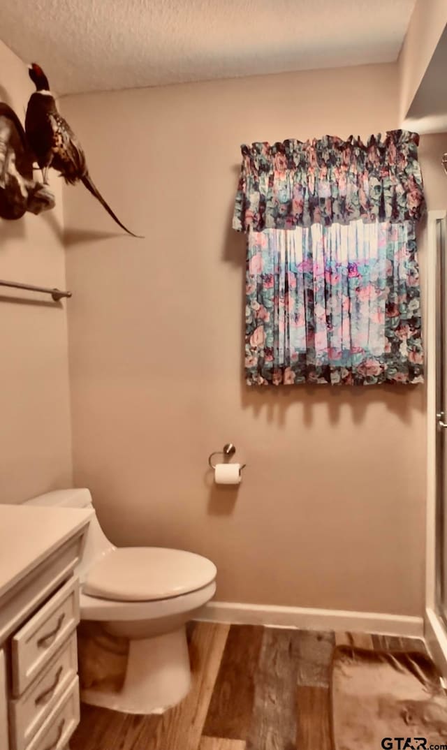 bathroom featuring a textured ceiling, vanity, hardwood / wood-style flooring, and toilet