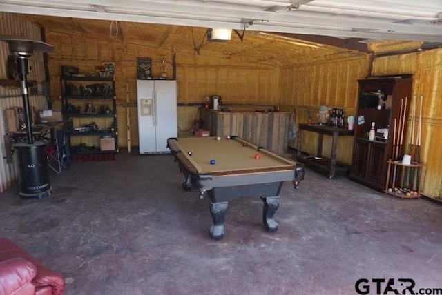 garage with a garage door opener, white fridge with ice dispenser, and wood walls