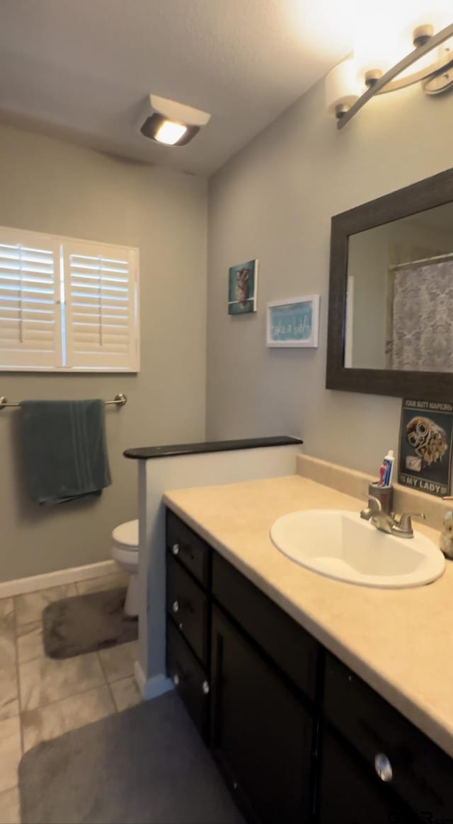 bathroom featuring tile patterned flooring, vanity, and toilet