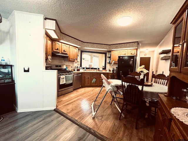 kitchen with a textured ceiling, stainless steel appliances, wood-type flooring, and sink