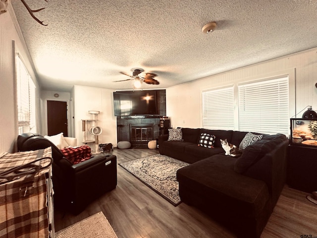 living room with a fireplace, dark wood-type flooring, a textured ceiling, and ceiling fan