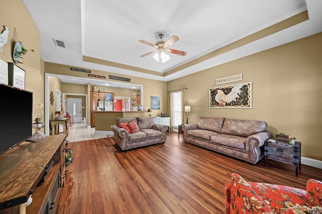 living room featuring hardwood / wood-style floors, ceiling fan, and a raised ceiling