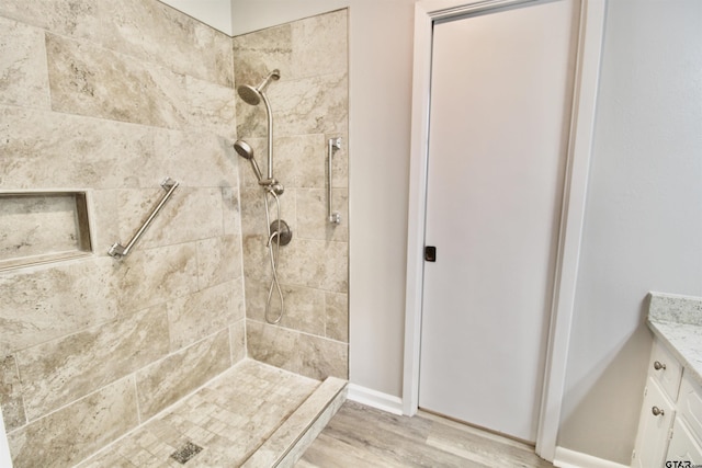 bathroom with vanity, a tile shower, and wood-type flooring