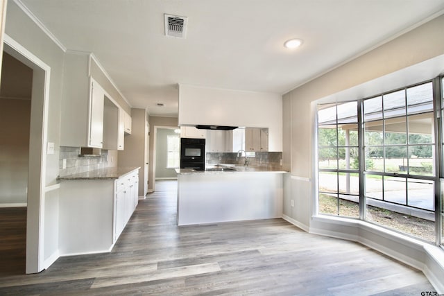 kitchen with hardwood / wood-style floors, sink, tasteful backsplash, white cabinetry, and kitchen peninsula