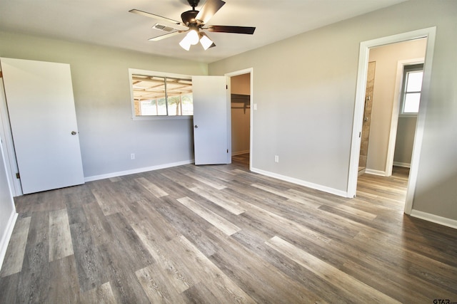 unfurnished bedroom with ceiling fan, wood-type flooring, and a spacious closet