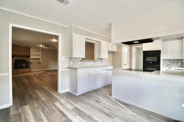 kitchen featuring black appliances, a brick fireplace, ceiling fan, tasteful backsplash, and white cabinetry