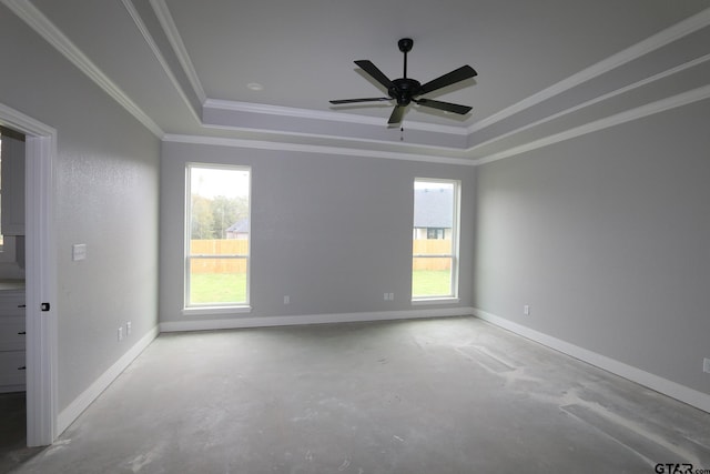 empty room featuring crown molding, concrete floors, and a raised ceiling