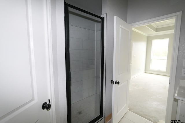 bathroom featuring a raised ceiling, ornamental molding, and walk in shower