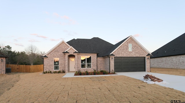 view of front facade with central AC unit, a garage, and a yard