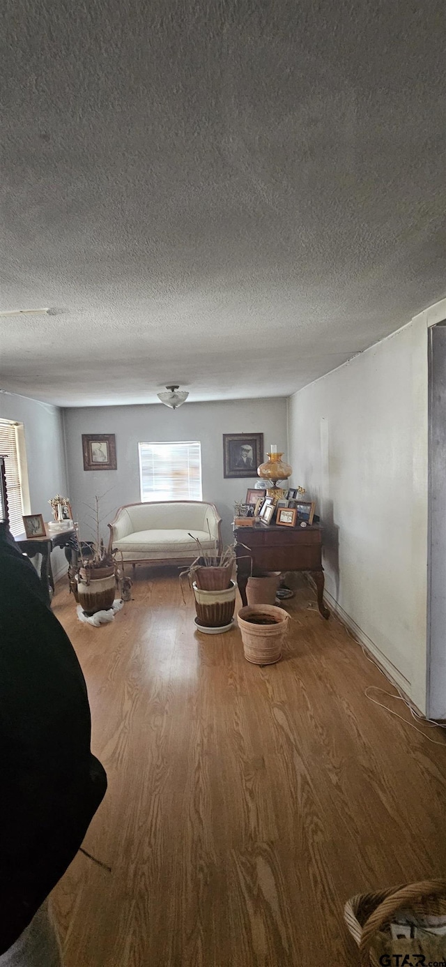 unfurnished living room featuring a textured ceiling and wood finished floors