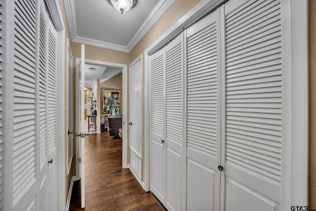 hall with dark hardwood / wood-style flooring, a textured ceiling, and ornamental molding