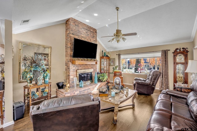 living room featuring wood-type flooring, a brick fireplace, lofted ceiling, and crown molding