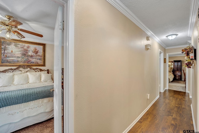 hall with a textured ceiling, ornamental molding, and dark wood-type flooring