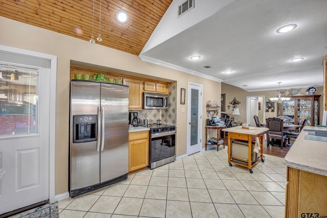 kitchen featuring appliances with stainless steel finishes, a chandelier, hanging light fixtures, lofted ceiling, and light tile patterned flooring