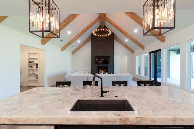 12240 Jazmin Cir, Flint, TX 75762 - kitchen with open floor plan, light stone counters, beamed ceiling, a chandelier, and decorative light fixtures