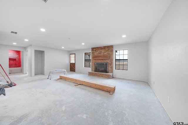 unfurnished living room featuring concrete flooring, recessed lighting, a brick fireplace, and visible vents