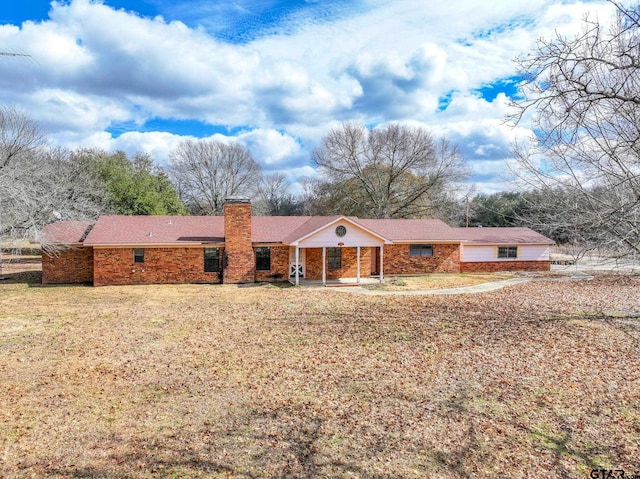 ranch-style home with a front lawn, a chimney, an attached garage, and brick siding