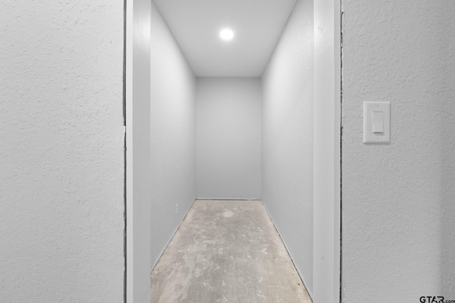 interior space featuring concrete flooring and a textured wall