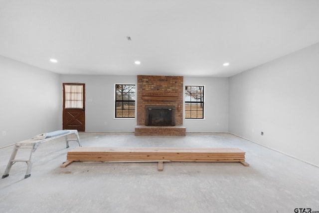 unfurnished living room featuring a brick fireplace, concrete floors, and recessed lighting