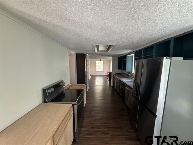 kitchen with appliances with stainless steel finishes, a textured ceiling, and dark hardwood / wood-style floors