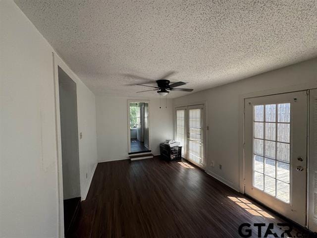 spare room with a textured ceiling, ceiling fan, dark wood-type flooring, and french doors