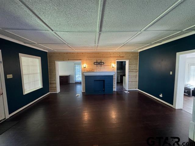 unfurnished living room with wood walls and dark hardwood / wood-style flooring