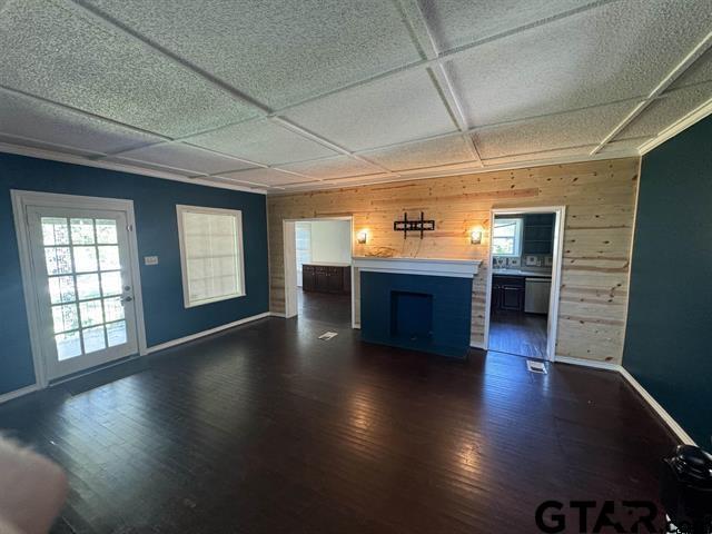 unfurnished living room with wood walls and dark wood-type flooring