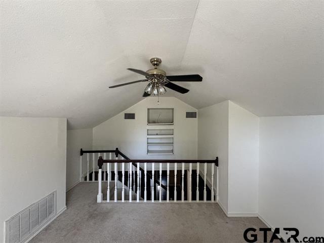 bonus room featuring carpet, a textured ceiling, vaulted ceiling, and ceiling fan