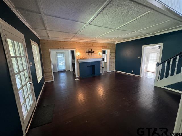 unfurnished living room featuring french doors, dark hardwood / wood-style floors, ornamental molding, and wood walls