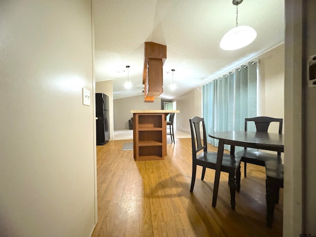 dining area with lofted ceiling, a textured ceiling, and light hardwood / wood-style floors