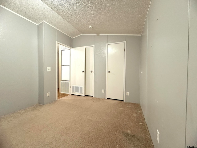 unfurnished bedroom with lofted ceiling, a textured ceiling, and light carpet