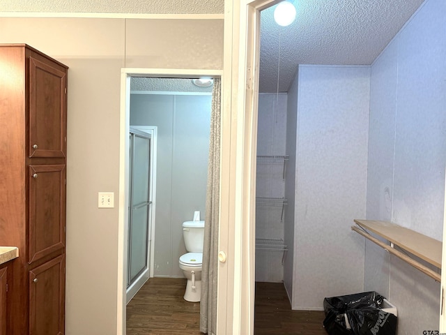 bathroom featuring wood-type flooring, a textured ceiling, toilet, and an enclosed shower