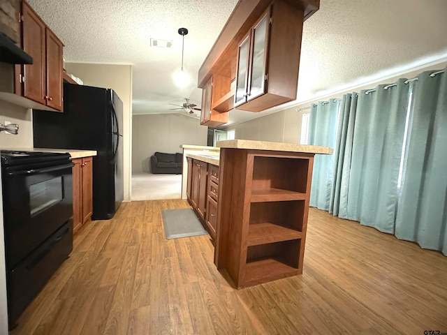 kitchen with hanging light fixtures, light hardwood / wood-style floors, a textured ceiling, and black appliances