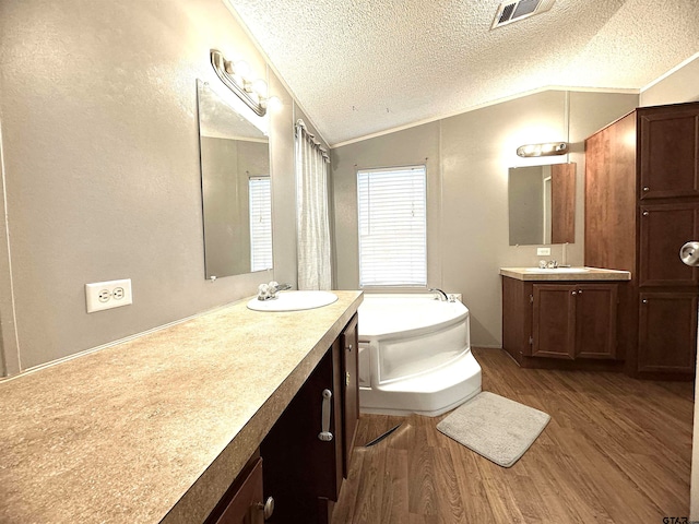 bathroom featuring a bathtub, lofted ceiling, wood-type flooring, and a textured ceiling