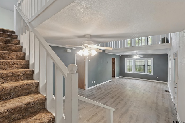 unfurnished living room with stairway, wood finished floors, baseboards, and ceiling fan