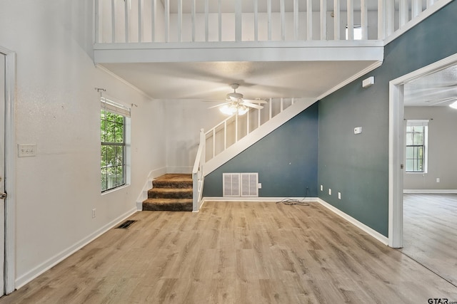 unfurnished living room featuring stairway, wood finished floors, visible vents, baseboards, and ceiling fan