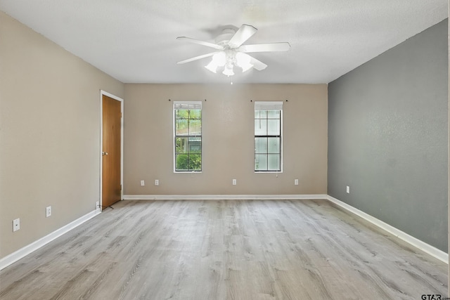 spare room featuring light wood finished floors, baseboards, and ceiling fan
