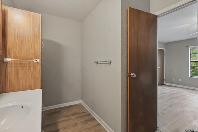 bathroom with baseboards, wood finished floors, and a sink