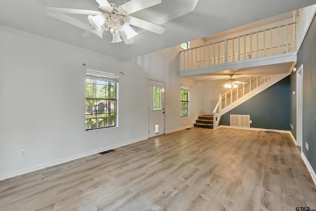 unfurnished living room featuring ceiling fan, stairs, visible vents, and plenty of natural light