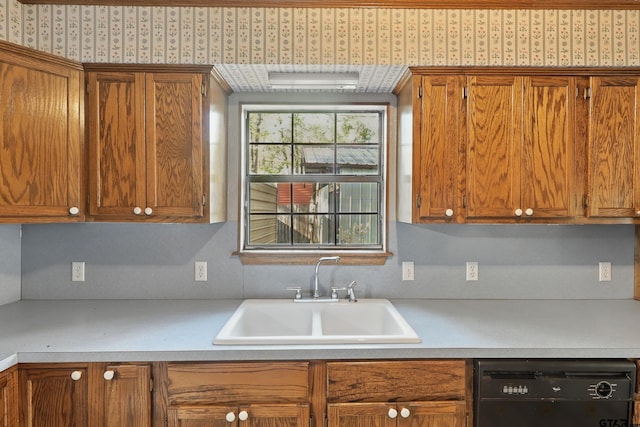 kitchen with black dishwasher, light countertops, brown cabinets, and a sink