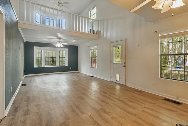 unfurnished living room featuring visible vents, a ceiling fan, baseboards, and a wealth of natural light