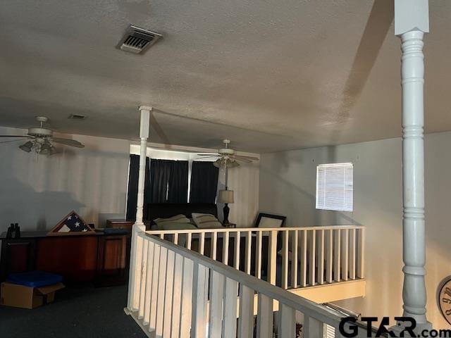 hall featuring a textured ceiling, an upstairs landing, and visible vents